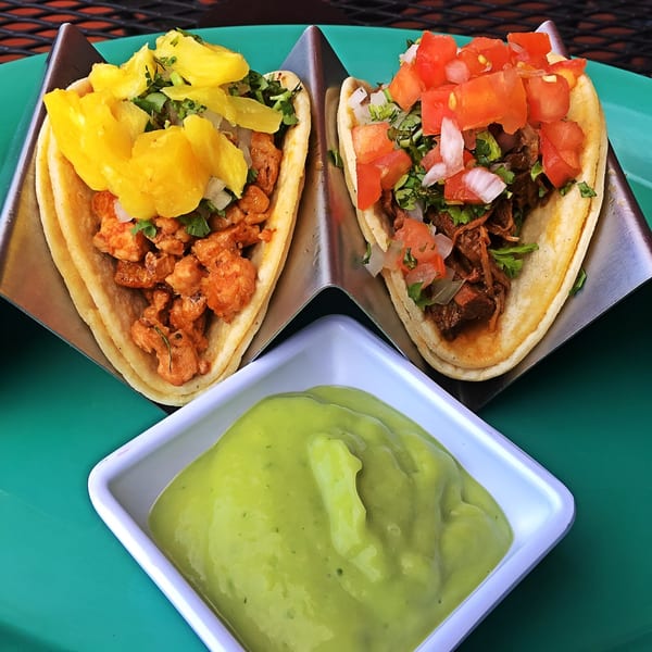Two Silly Serrano Mexican Restaurant tacos, one with pineapple, the other with tomatoes, and a side of guacamole.