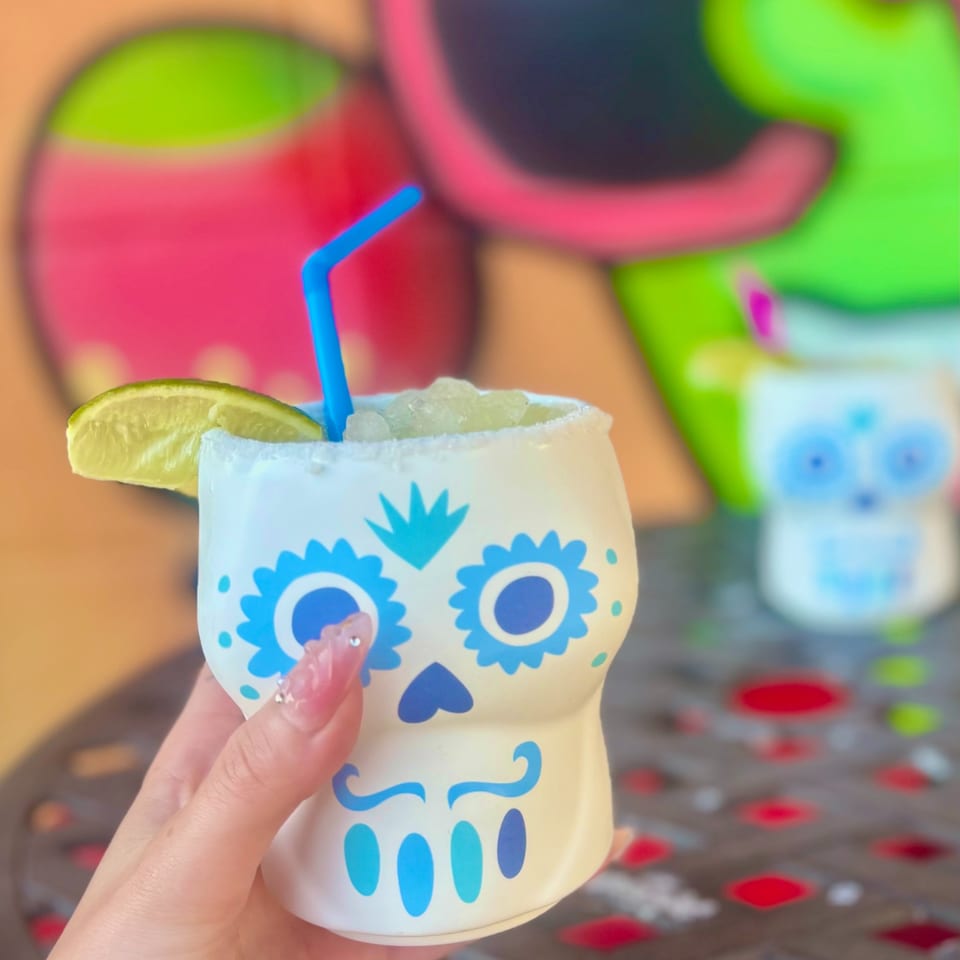 Hand holding a Silly Serrano Mexican Restaurant margarita in a sugar skull mug with a lime.